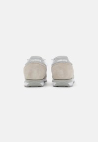 Baskets blanches et gris clair avec des accents en suède beige. Comprend un talon rembourré, une semelle texturée et un logo de marque à l'arrière.