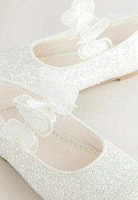 Balerini albi cu o textură sclipitoare, decorați cu trei fluturi albi din țesătură pe curea. Căptușeală interioară moale, vârf rotunjit.
