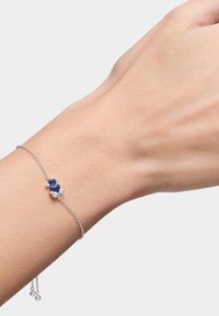 Pulsera de cadena de plata con cuentas azules y blancas, que presenta un diseño delicado y longitud ajustable, exhibiendo una textura suave y un brillo sutil.