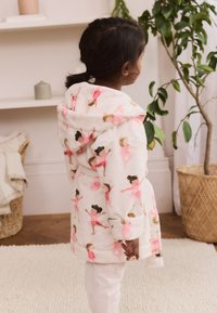 Fehér, bolyhos köntös rózsaszín balerina mintákkal, kapucnival és kötős övvel. Fehér nadrággal párosítva, amely apró mintákat ábrázol.