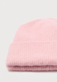 Berretto lavorato a maglia di un delicato rosa chiaro, piegato, su uno sfondo bianco semplice.