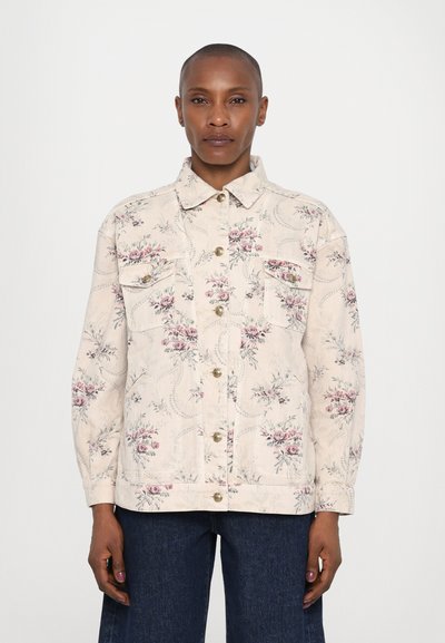 Veste en denim crème à motif floral avec deux poches poitrine et boutons dorés, présentant un col et des manches longues.
