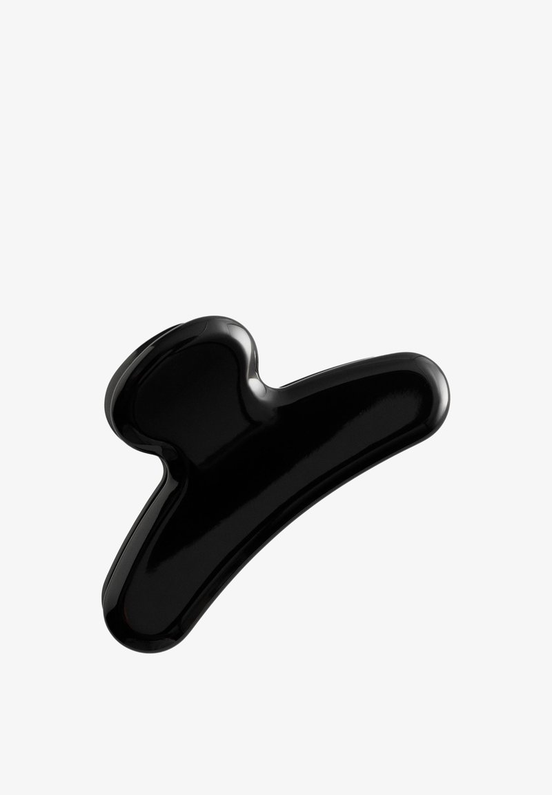 Pince à cheveux en plastique noir brillant avec larges griffes courbées, isolée sur fond blanc.