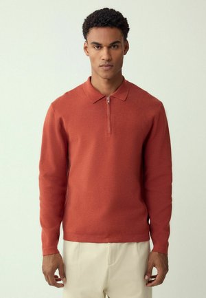 Langärmeliges Poloshirt in Rostfarbe mit einem Reißverschluss am Kragen, gefertigt aus einem weichen, strukturierten Stoff. Verfügt über eng anliegende Ärmel und einen geraden Saum.