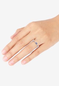 Sterling silverring med en böjd band som har en central blå ädelsten och små accentstenar på vardera sida. Slät yta.