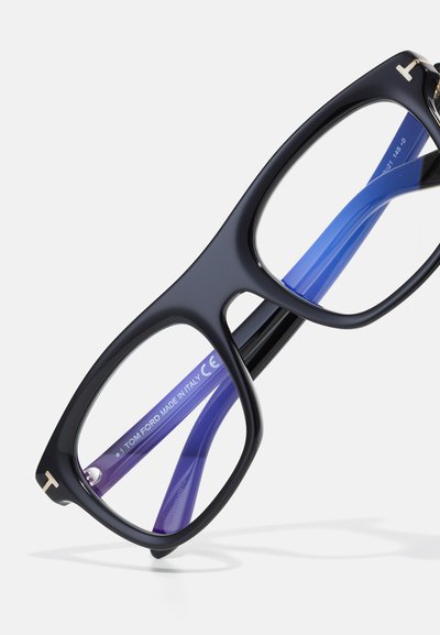 Óculos de grau retangulares pretos com acessórios dourados. As hastes interiores apresentam um degradê do azul para o roxo. Lentes transparentes. Marca Tom Ford visível.
