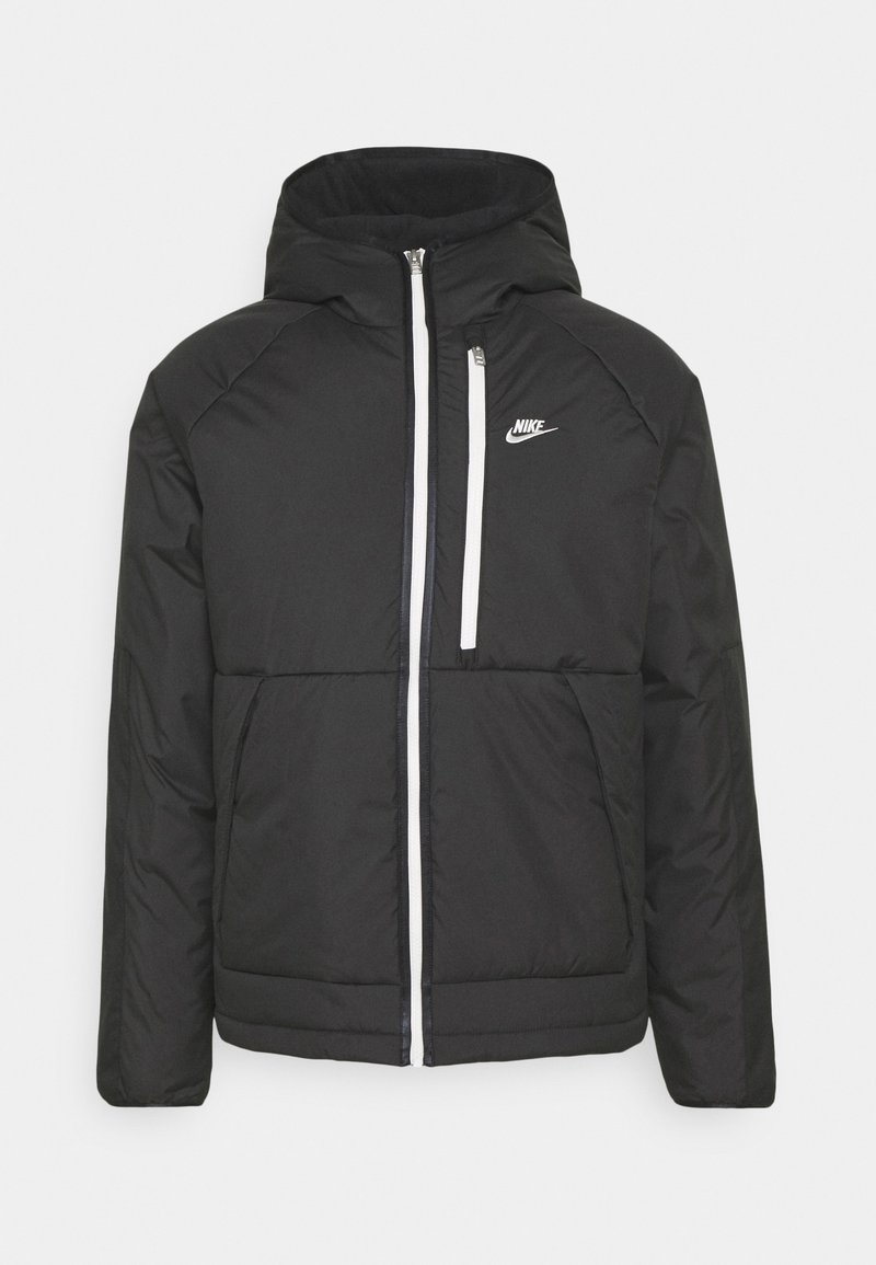 Schwarze Daunenjacke mit Kapuze, Reißverschluss, weißen Akzenten und kleinem Nike-Logo auf der linken Brust. Verfügt über eine gesteppten Textur.