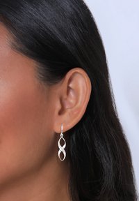 Silberne Hängeohrringe im design eines miteinander verflochtenen Schlaufen, mit kleinen Kristallakzenten für zusätzlichen Glanz. Glatte, glänzende Textur und leicht.