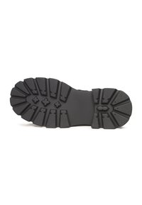 Suela de zapato de caucho negro con surcos profundos, que presenta patrones de agarre texturizados y acentos distintivos para tracción en diversas superficies.