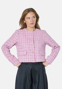 Rožinės spalvos tvido striuk�ė su tekstūruotu raštu, apvaliu iškirpimu ir auksinėmis sagomis. Turi dvi priekinės kišenes ir ilgomis rankovėmis.