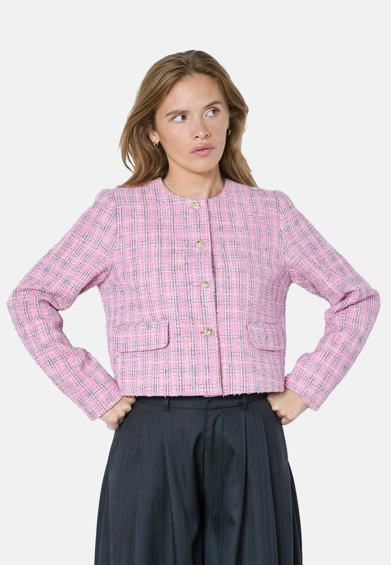 Rožinės spalvos tvido striukė su tekstūruotu raštu, apvaliu iškirpimu ir auksinėmis sagomis. Turi dvi priekinės kišenes ir ilgomis rankovėmis.