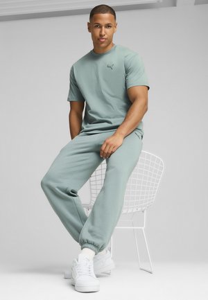 Light green cotton t-shirt with a round neck and small logo, paired with matching joggers featuring elastic cuffs and side pockets. White sneakers.