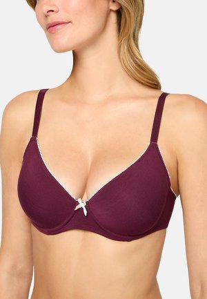 Woman wearing a plum-colored, lightly padded bra with thin straps and a small white bow detail at the center front.
