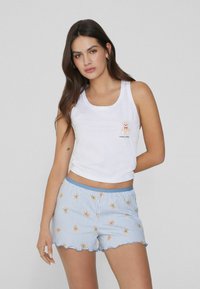 Witte katoenen tanktop met een berenafbeelding en de tekst "sweet teddy"; gecombineerd met blauw-witte gestreepte shorts met een teddybeerpatroon en een gegolfde zoom.