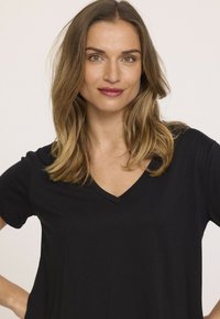 T-shirt noir à col en V, avec des manches courtes, une coupe décontractée et une texture lisse, agrémenté d'un design simple et sans motifs.