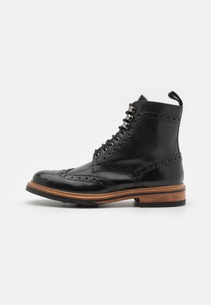Schwarze Leder-Brogue-Stiefel mit dekorativen Perforationen, hohem Knöcheldesign, Metallösen und einem Akzent aus Holzsohle.