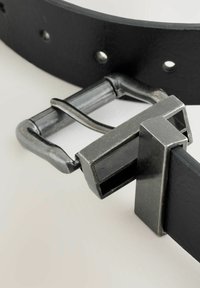 Cinturón de cuero negro que presenta una hebilla metálica rectangular con un acabado cepillado y un lazo para un cierre seguro, detallado con agujeros.
