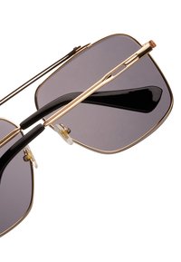 Occhiali da sole oro e neri con lenti grigie; forma rettangolare, montatura in metallo e uniche naselli; design elegante con hardware minimale.