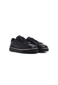 Sneakers in pelle nera con finitura liscia, punta rotonda, design con lacci e suola in gomma spessa con una striscia metallica decorativa.
