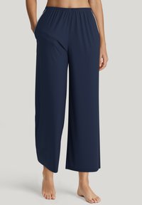 Marineblauwe broek met wijde pijpen, elastische tailleband, zachte textuur en zijzakken, met contrasterende piping langs de naden.