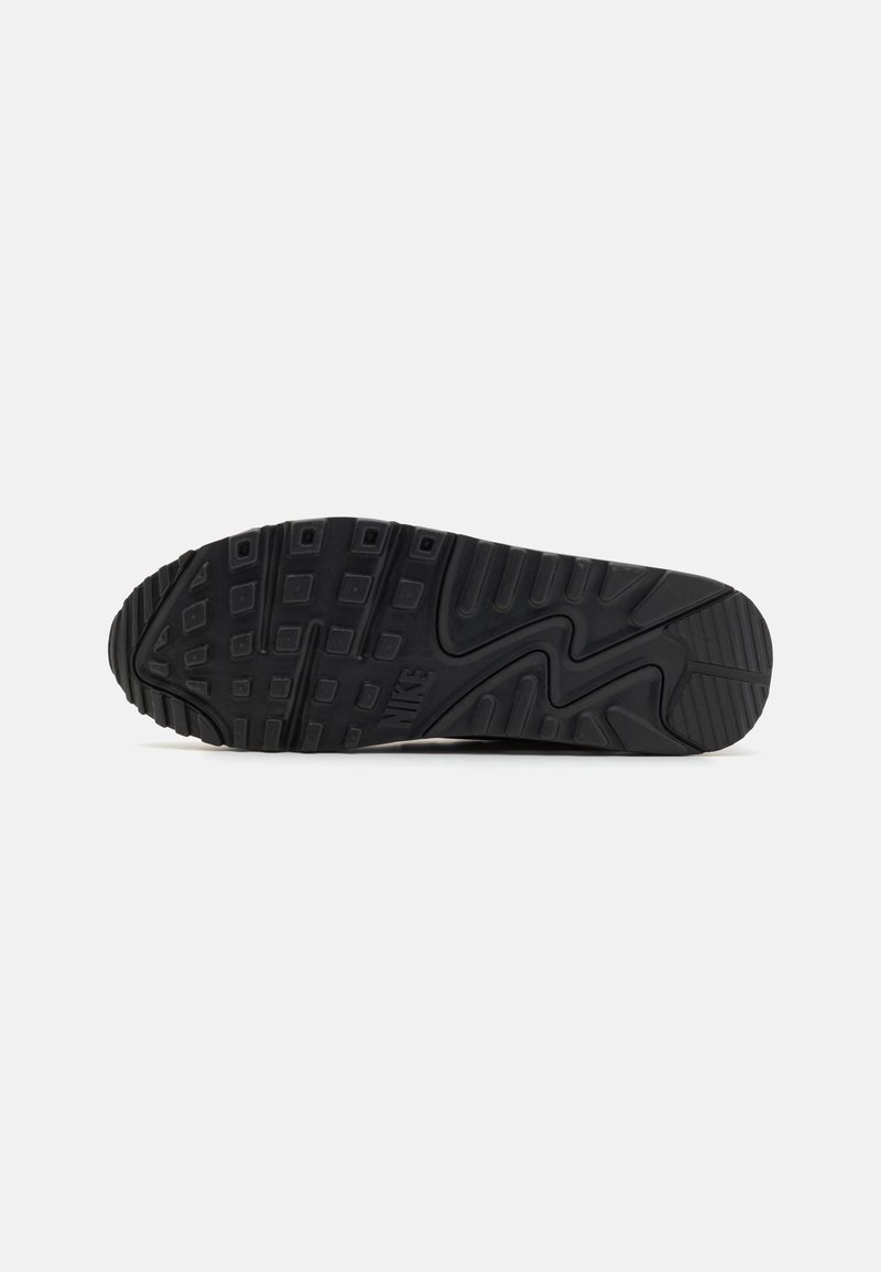 Semelle de basket en caoutchouc noir avec des motifs texturés, présentant des designs rectangulaires et en zigzag pour une adhérence et une stabilité accrues. Forme athlétique standard.