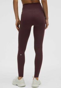 Kõrge talje ja tumesinised legginsid sujuvast ja venivast kangast, millel on logo pahkluul ja sobiv disain.