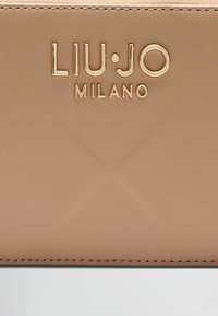 Bež novčanik od kože s uzorkom dijamanta, uvučenim logotipom "LIU·JO MILANO" u zlatnoj boji i diskretnim detaljima šivanja.