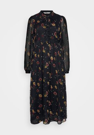 Mustaline mustriga must kleit, millel on punased, kollased ja valged lillemustrid. Omab pikki, läbipaistvaid täppidega varrukaid ja lipsuga kraed. Nööbiga esiosa.