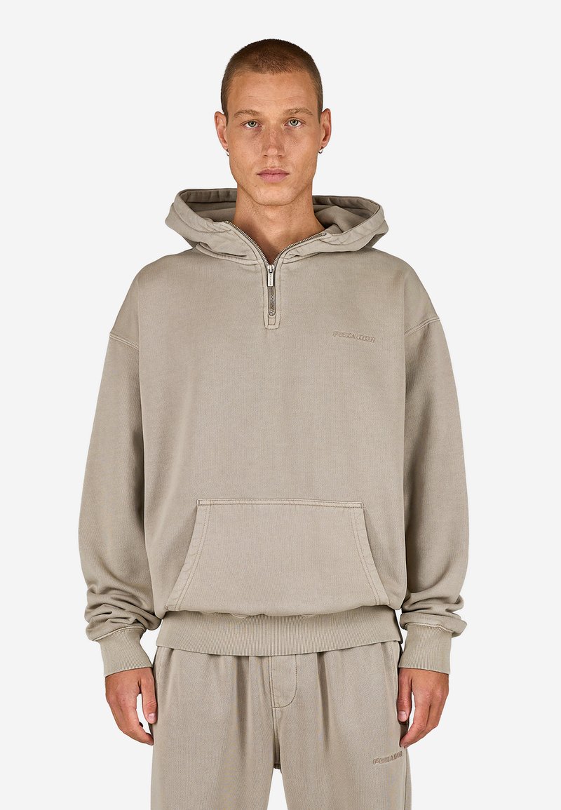 Béžová mikina s kapucňou a polovičným zipsom vpredu, klokanie vrecko a rebrované manžety a spodný lem. Mäkko tkaný materiál s jemným brandingom.