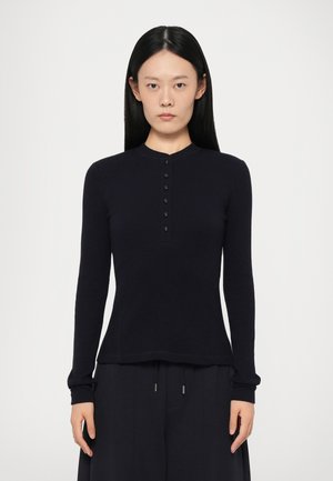Navy long-sleeve top with a round neckline and a button placket. Made from a soft material with a slim fit and ribbed cuffs.