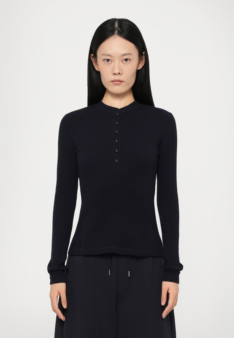 Tummansininen pitkähihaisessa paidassa on pyöreä kaula-aukko ja nappilista. Se on valmistettu pehmeästä materiaalista, slim fit -malli ja ribbireunaiset hihat.