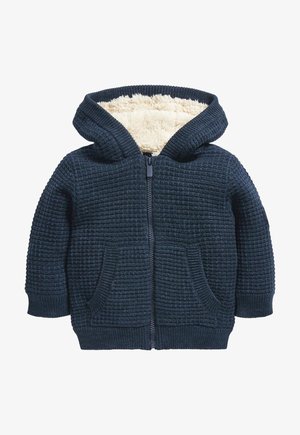 Sudadera con cremallera en color marino, con un exterior de punto texturizado, forro de felpa suave, bolsillos frontales y capucha. Presenta puños y dobladillo de canalé.