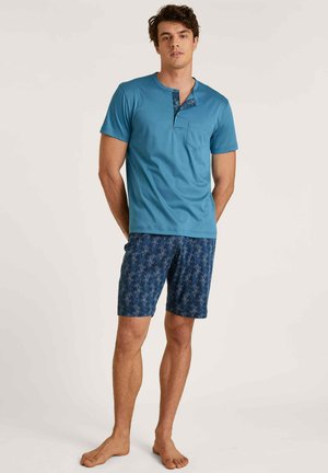Ensemble de pyjama en coton bleu pour homme ; haut à manches courtes avec une poche et un bouton décoratif, associé à un short marine avec un motif corail.