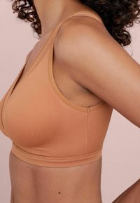 Bh i en varm beige färg med ett mjukt, stretchigt tyg. Har en djup V-ringning och breda axelremmar för stöd.