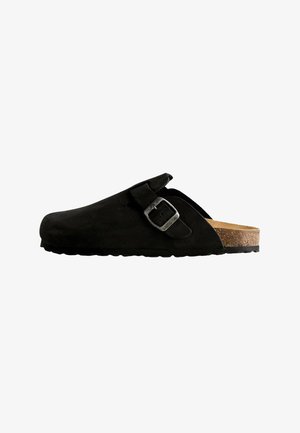 Black suede clog with an adjustable metal buckle, cork footbed, textured sole, and a rounded toe design for comfort and support.