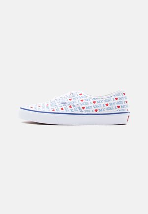 Baskets Vans basses blanches avec un texte bleu et des cœurs rouges répétant le motif "J'aime mes Vans" sur la tige en tissu.