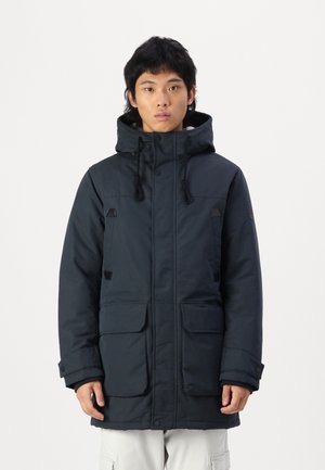 Navy winter parka featuring a hood, two large front pockets, snap and zipper closures, contrasting black accents, and a textured surface.