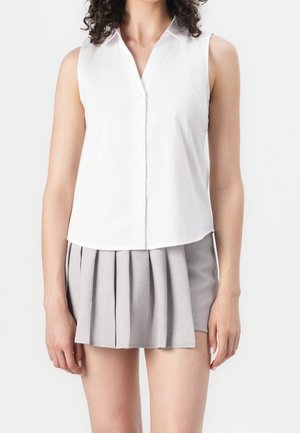 White sleeveless blouse with a buttoned front, paired with a pleated gray skirt. Smooth fabric, tailored fit, and classic collar design.