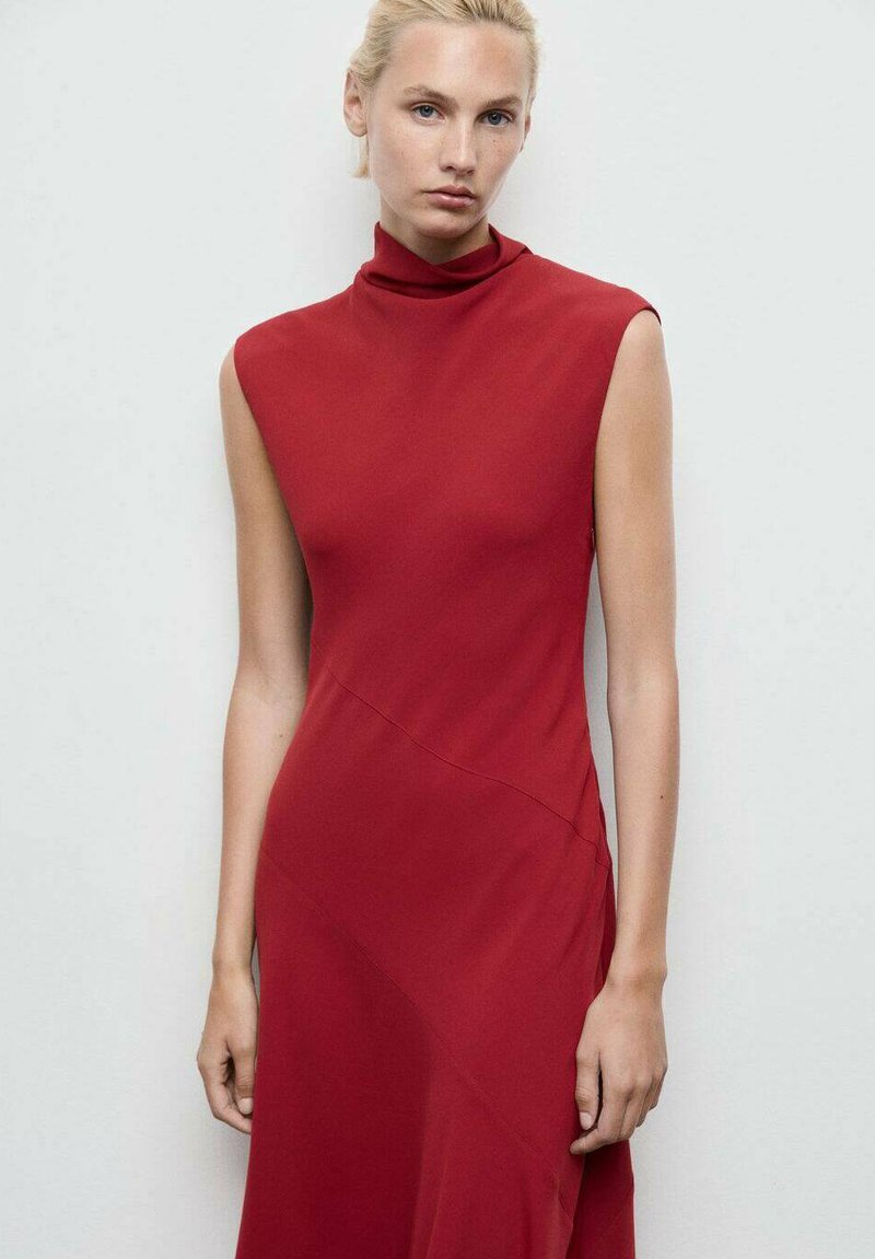 Rochie roșie, fără mâneci, cu gâtul înalt și ajustat. Fabricată dintr-un material fin, prezintă o cusătură diagonală și o siluetă în linie A.