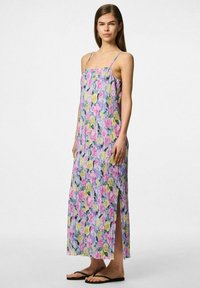Vestido largo floral con tirantes finos, con textura plisada en rosa, amarillo y verde, con aberturas laterales para facilitar el movimiento.