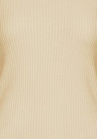 Primo piano di un tessuto in maglia ribbed beige con righe texture verticali.