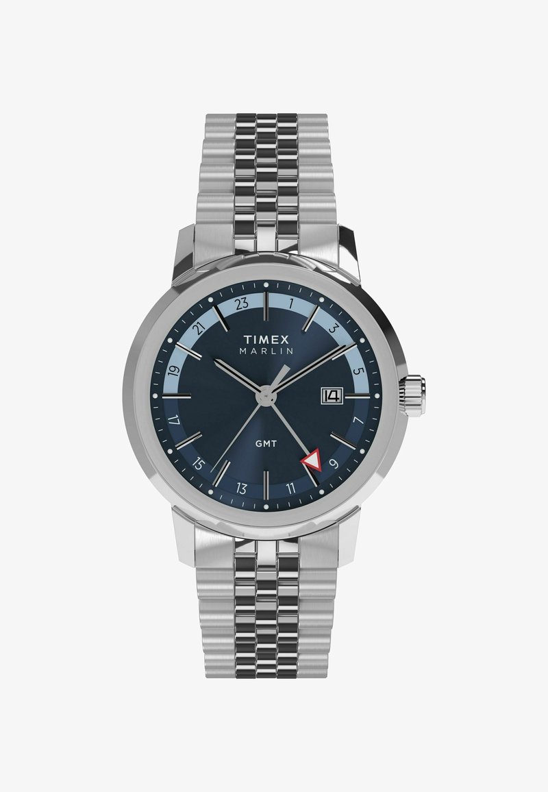 Timex Marlin óra rozsdamentes acél karkötővel, sötétkék számlappal, ezüst díszítéssel, dátumkijelzővel és piros háromszög GMT mutatóval.