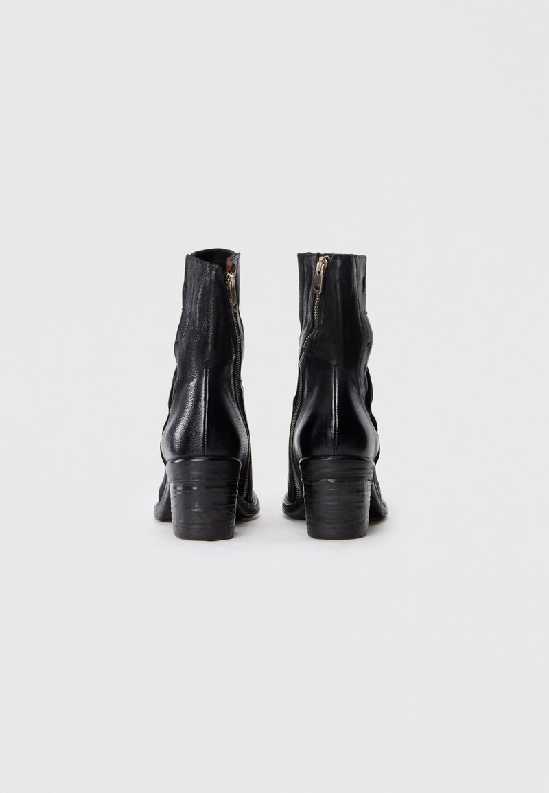 Bottines en cuir noir avec fermetures éclair sur les côtés, finition texturée et talons empilés. Le design présente une forme légèrement effilée.
