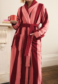 Red and pink striped bathrobe made of soft terry cloth, featuring a belted waist, loose sleeves, and a front pocket.