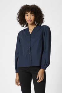 Chemise bleu marine à boutons avec des manches bouffantes longues, présentant un décolleté en V texturé et un tissu lisse ; associée à un pantalon noir.