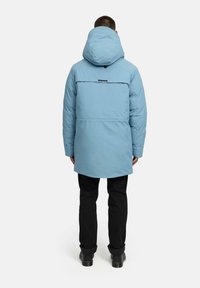 Svetlomodrá, dlhá kapucňová bunda s zadným prešívaním a čiernym akcentom. Skombinovaná s čiernymi nohavicami a plochými topánkami.