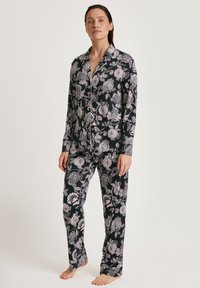 Zwart pyjama set met een bloemenpatroon in pink en wit, bestaande uit een overhemd met knoopsluiting en rechte broekspijpen, gemaakt van een zachte stof.