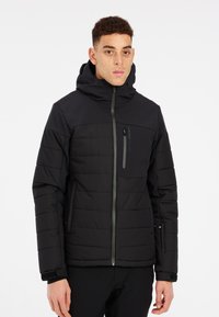 Černá péřová bunda s kapucí, obsahující prošívané části, přední zip a kapsu na zip na hrudi. Vyrobena z izolačního materiálu.