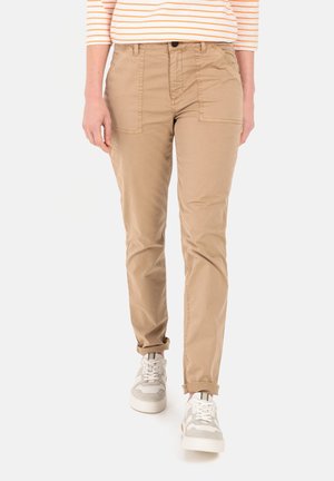 Khaki Chinos mit schlanker Passform, ausgestattet mit Fronttaschen und einem glatten Baumwoll-Mischgewebe. Kombiniert mit weißen Sneakers für einen lässigen Look.