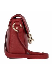 Borsa a tracolla in pelle rossa con texture, chiusura in oro, tracolla regolabile e dettagli in metallo circolari. La vista laterale mette in evidenza il design compatto.